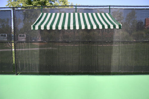 Green tennis court with a striped green and white awning overhead, providing shade near the court's fence. Ideal for enhancing player comfort.