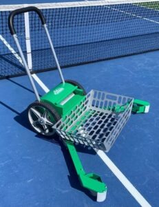 Green tennis ball pickup cart on a blue court, positioned near the net, designed for efficiently collecting tennis balls.