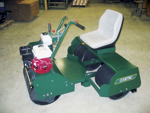 Green landscaping roller with a seat, handlebars, and a small engine; designed for leveling soil and turf in garden maintenance.