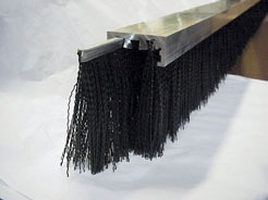 Industrial brush with a metal base and long black bristles, designed for cleaning or sealing gaps. Relevant for discussions on equipment maintenance.