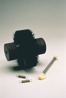 Black cylindrical brush with bristles, a metal rod, and two small white clips. Used for maintenance or assembly in mechanical contexts.
