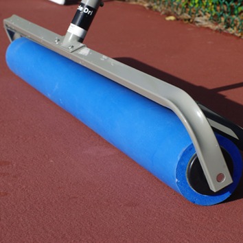 Blue court roller on a red tennis court, used for leveling and smoothing surfaces after maintenance. Essential for maintaining court conditions.