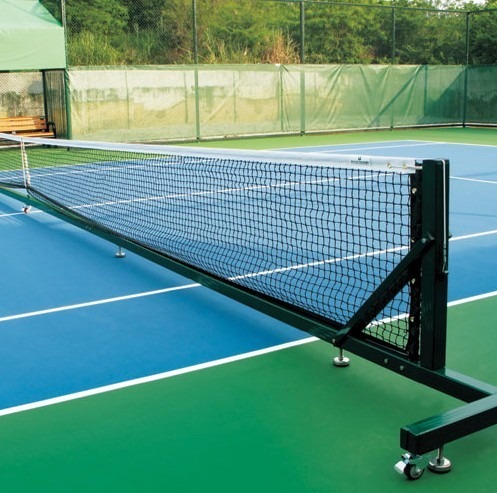 Tennis court with a net in the foreground, showcasing the vibrant blue and green surfaces. The net highlights the ready setup for a game.